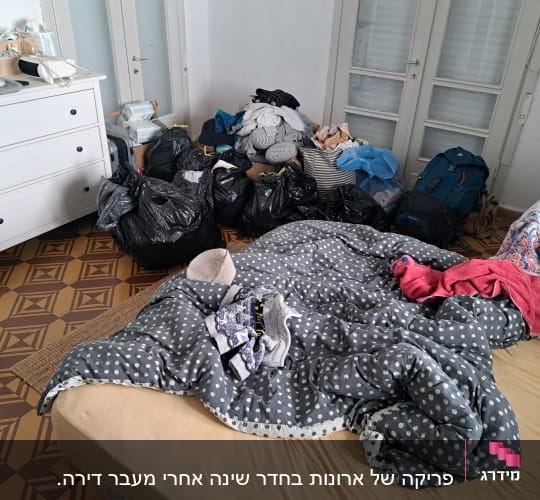 חדר עם שקיות זבל, בגדים מפוזרים ומגבות על מיטה